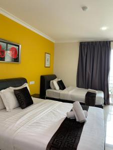 a hotel room with two beds and a yellow wall at Lumuda Hotel in Lumut
