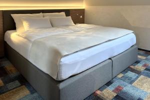 1 cama grande con sábanas y almohadas blancas en Duran Penzion, en Hradec Králové