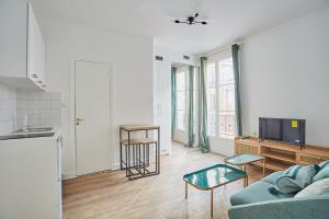 een woonkamer met een bank en een tv bij Residence Neuilly Bois de Boulogne by Studio prestige in Neuilly-sur-Seine