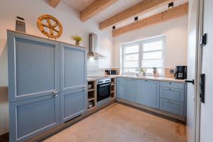 a large kitchen with blue cabinets and a window at Ferienpark Harkebrügge Haus Borkum in Barßel