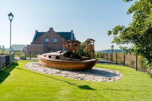 a wooden boat sitting in the grass next to a house at Ferienpark Harkebrügge Haus Borkum in Barßel