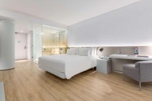 a white bedroom with a large white bed and a chair at nhow Rotterdam in Rotterdam