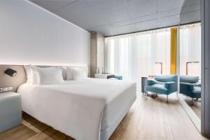 a white bedroom with a large white bed and a desk at nhow Rotterdam in Rotterdam