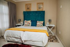 a bedroom with a large bed with a blue headboard at Gosheni Villas in White River