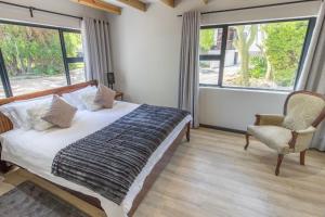 a bedroom with a bed and a chair and windows at Mimosa Lodge in Montagu