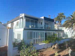 a white house on the beach with palm trees at Apartamento Oasis Palmeras 4 in San Bartolomé