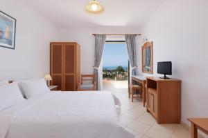 a bedroom with a bed and a desk and a television at Century Resort in Acharavi