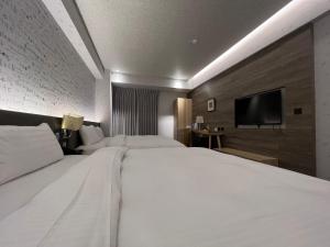 a hotel room with two beds and a flat screen tv at DLInn Hotel in Taichung