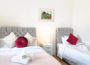 two beds in a bedroom with red and white pillows at City Lodge Shadwell in London