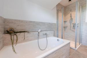 a bathroom with a bath tub and a shower at Ferienpark Harkebrügge Haus Juist in Barßel +24 photos