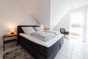 a bed with white sheets and pillows in a room at Ferienpark Harkebrügge Haus Juist in Barßel