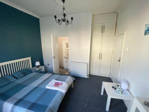 a bedroom with a blue bed and a table at The Bay En-suite Room in Plymouth