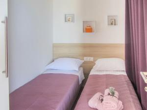 2 Betten in einem kleinen Zimmer mit rosa Vorhängen in der Unterkunft Mobile home Opal 2 in Biograd na Moru
