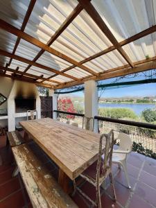 a wooden table on a balcony with a view of the water at Kadie's Landing House - Living The Breede in Malgas