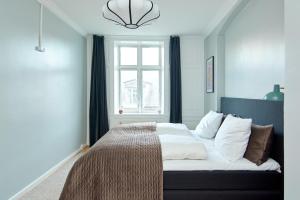 een slaapkamer met een bed met witte lakens en een raam bij Large Modern Flats By Meat Packing District in central Copenhagen in Kopenhagen