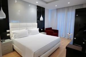 ein Schlafzimmer mit einem weißen Bett und einem roten Stuhl in der Unterkunft Hotel Luxury in Ksamil + 23 Fotos