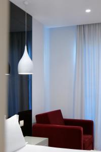 ein Wohnzimmer mit einer Couch und einem roten Sessel in der Unterkunft Hotel Luxury in Ksamil