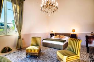 sypialnia z łóżkiem, dwoma krzesłami i żyrandolem w obiekcie Villa Angelina - charming rooms & apartments w Trapani