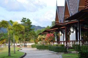 un edificio con árboles y flores delante de él en PARADIS VERT en Ban Khao Thong