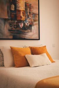 Una cama con almohadas naranjas y un cuadro encima. en Casa da Bia, en Conceição