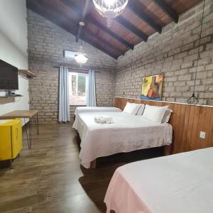 a bedroom with two beds and a brick wall at Bosque São Francisco in Chapada dos Guimarães