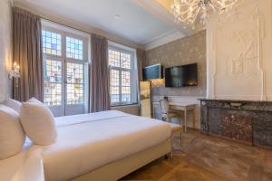 a bedroom with a bed and a desk and a television at Amrâth Hotel Bigarré in Maastricht