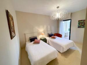 a bedroom with two beds and a chandelier at Luxurious 2 bedroom apartment with Spa facilities in Benahavís