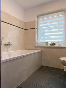 een badkamer met een bad, een toilet en een raam bij Gästewohnung 3 in Oschersleben
