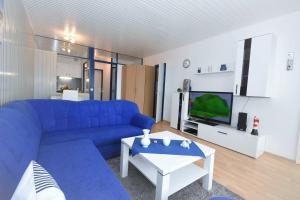 ein Wohnzimmer mit einem blauen Sofa und einem TV in der Unterkunft Apartementhaus Panoramic in Sierksdorf