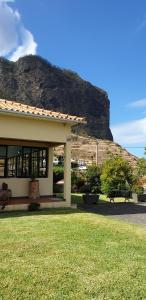 a building with a bench in front of a mountain at House pc in Porto da Cruz