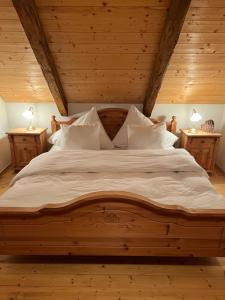 Un dormitorio con una gran cama de madera con almohadas blancas. en Das Klimachalet - CO2 neutral urlauben, en Rennweg