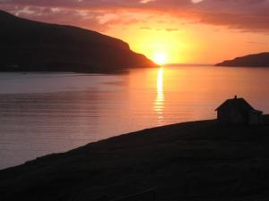 einen Sonnenuntergang über einem Wasserkörper mit einem Haus in der Unterkunft Liljulon - Views - Location in Ljósá