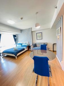 a room with two beds and a table and blue chairs at Abreeza Place by Chriza in Davao City