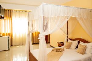 a bedroom with a canopy bed with white drapes at Amazone Hotel Tulear in Toliara