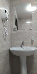 W łazience znajduje się biała umywalka i lustro. w obiekcie Casa Familiei w Braszowie