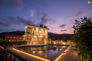 a house with a swimming pool at night at Eden Garden in Alibaug