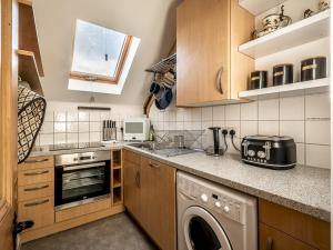 cocina con armarios de madera, lavadora y secadora en Pass the Keys Meldon View Period Dartmoor apartment with large roof terrace, en Newton Abbot
