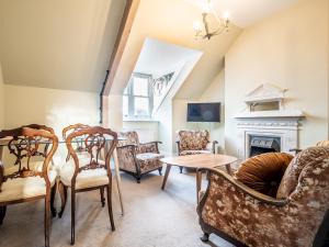 sala de estar con sillas, mesa y chimenea en Pass the Keys Meldon View Period Dartmoor apartment with large roof terrace, en Newton Abbot