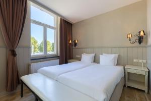 a bedroom with a large white bed and a window at Amrâth Hotel Bigarré in Maastricht