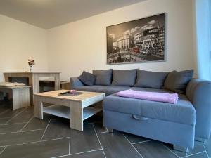 a living room with a blue couch and a table at Gästewohnung 4 in Oschersleben +1 photo
