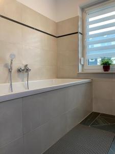 ein weißes Bad mit einer Badewanne und einem Fenster in der Unterkunft Gästewohnung 4 in Oschersleben