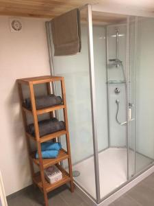 a bathroom with a shower and a wooden shelf with towels at La Maisonnette : charmante maison indépendante in Salgesch