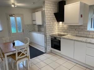 a kitchen with white cabinets and a table and a table and chairs at House in Slades Green