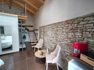 Habitación con pared de piedra, mesa y sillas. en Dimora DarSenso, en Albaretto Della Torre 