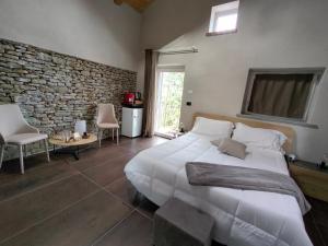 a bedroom with a large white bed and a stone wall at Dimora DarSenso in Albaretto Della Torre 