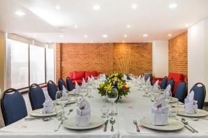 einen Konferenzraum mit einem langen Tisch mit Gläsern und Blumen in der Unterkunft Hotel Hill House Usaquén in Bogotá
