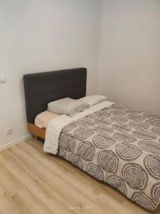 a bed with a black headboard in a bedroom at Logement complet à Villeurbanne in Villeurbanne