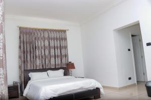 a white bedroom with a bed and a window at the Waldorf Astoria 5 Alema avenue in Accra