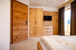 - une chambre avec des placards en bois et un lit avec une télévision dans l'établissement Unterkoller Bauernhaus Chalet, à Bischofshofen