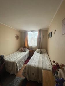 a bedroom with two beds and a window at Departamento en Condominio Cerrado La Florida in Santiago